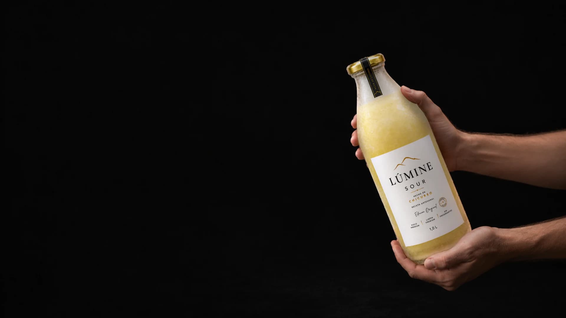 Dos manos sostienen una botella de Lúmine Sour, listas para agitarla